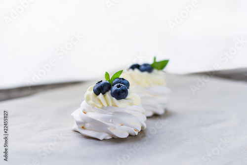 Pavlova meringue cake with figs, blueberries and mint leaves on a wooden background.