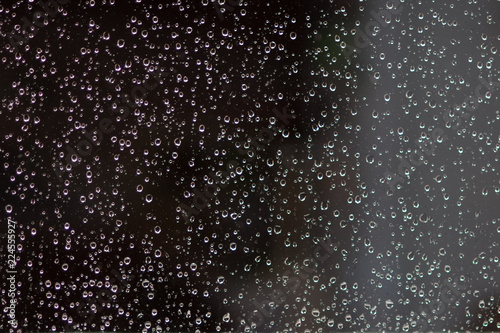 Rain drops on the window glass at night time.