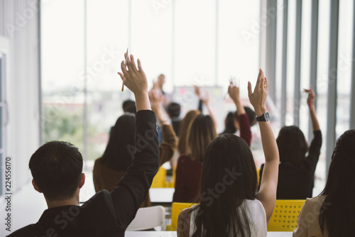 Raised up hands and arms of large group in seminar class room at Conference