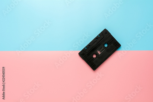 black tape cassette on blue and pink background.