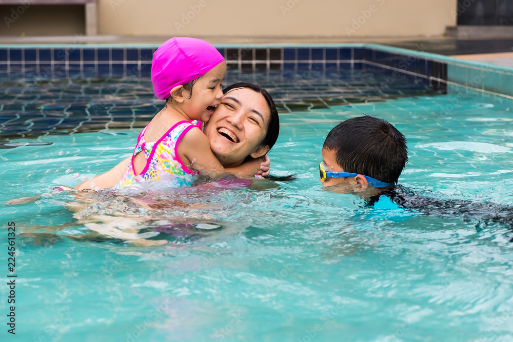 family spent time to swim in swimming pool. they enjoy playing together with laughing