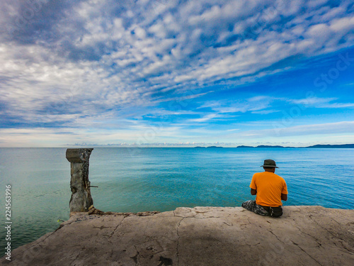 Fisherman siting on jetty bridge with blue sky at the sea