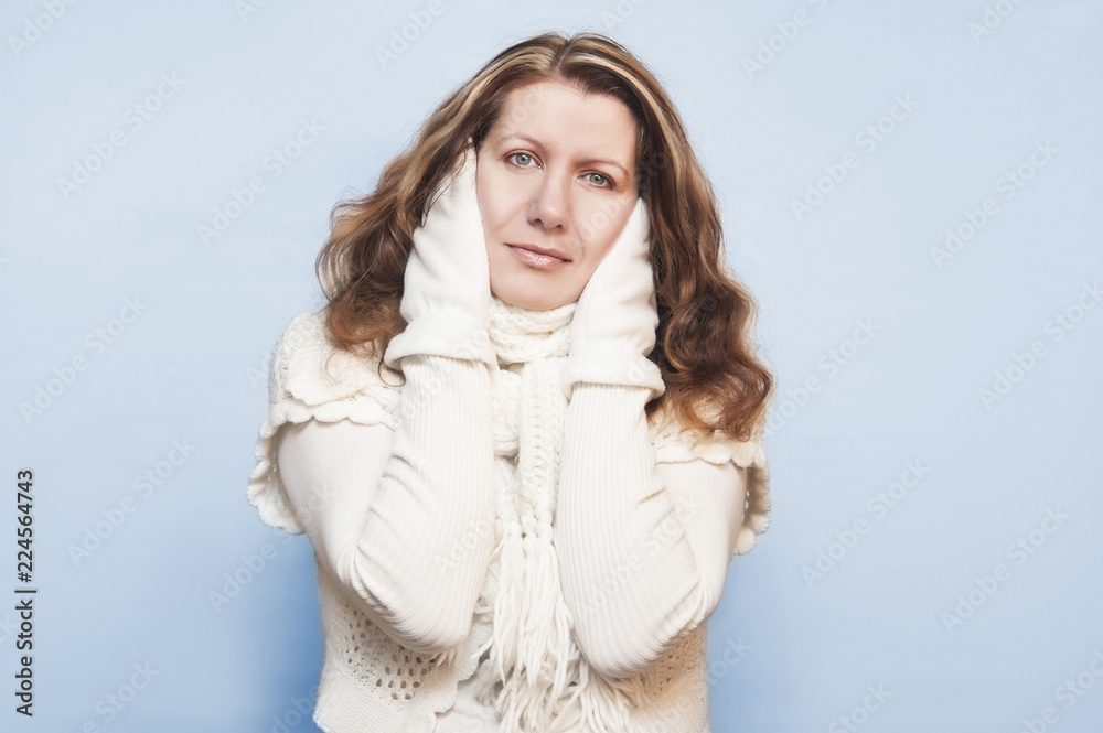 Beautiful woman in white warm clothes with a scarf on the neck and winter gloves on a light background Beautiful woman in white warm clothes with a scarf on the neck and winter gloves on a light background