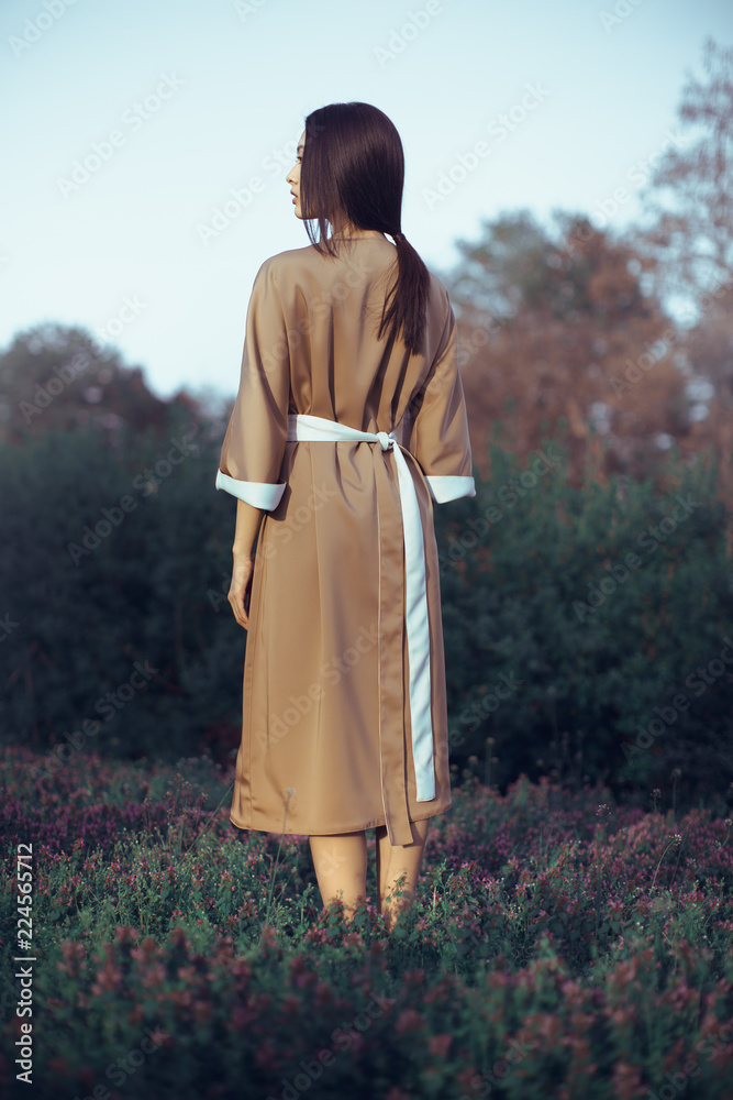 Fotka „Asian woman wearing traditional japanese kimono outdoors in park.  Stylish graceful japanese model posing outdoors in fashionable dress. Young  girl standing on flower field in full length. Back view“ ze služby