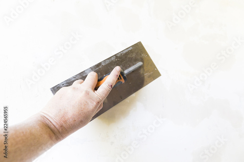 Photography Woman hand with old metal spatula to equalize plaster filler on the wall