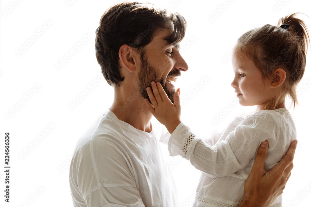 Parenthood. Family. Love. Dad is holding his little daughter in his arms and smiling. Girl is touching dad's beard. On white background Parenthood. Family. Love. Dad is holding his little daughter in his arms and smiling. Girl is touching dad's beard. On white background