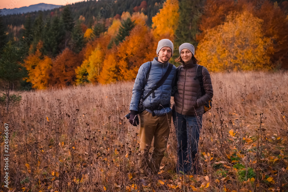 Young couple enjoying beautiful autumn forest in the mountains
