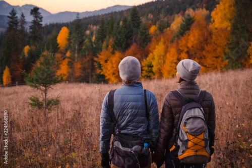 Young couple enjoying beautiful autumn forest in the mountains