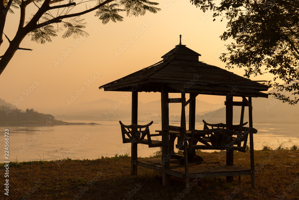 sillhouette of waterfront Pavilion in the morning.River and mountain background. sillhouette of waterfront Pavilion in the morning.River and mountain background.