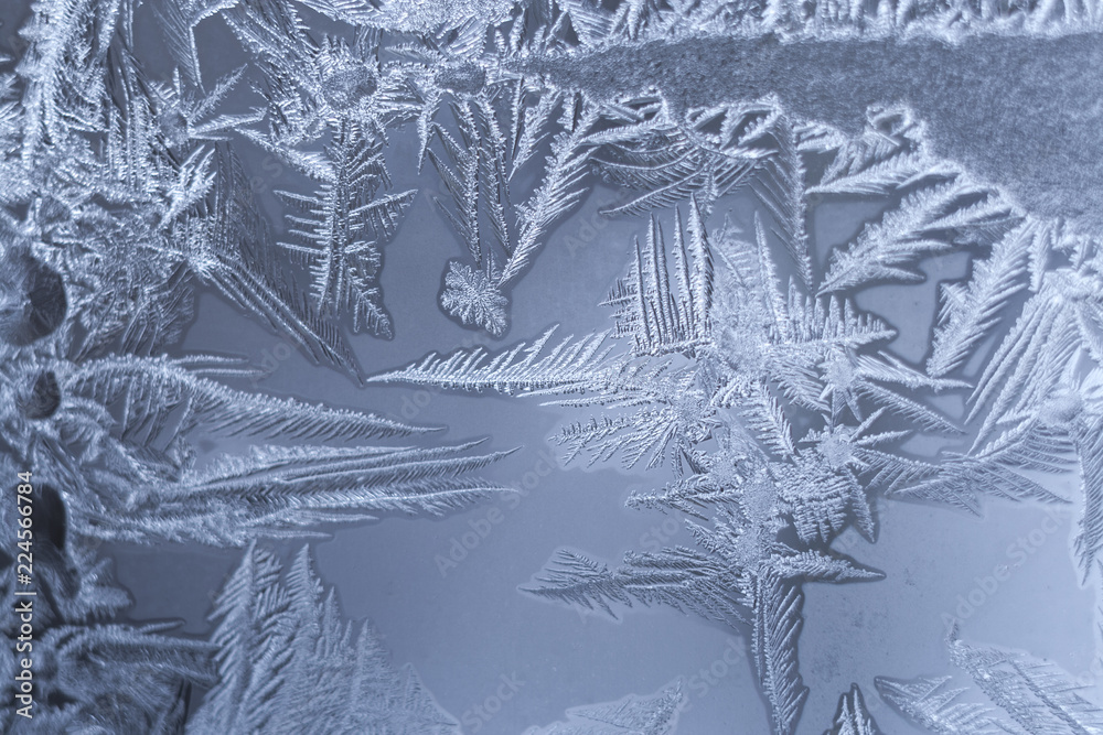 Winter frosty pattern with openwork sharp parts on frozen window.