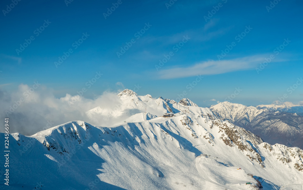 Beautiful snowy ridge of caucasus mountains under clear blue sky in Krasnaya Polyana, Sochi, Russia.