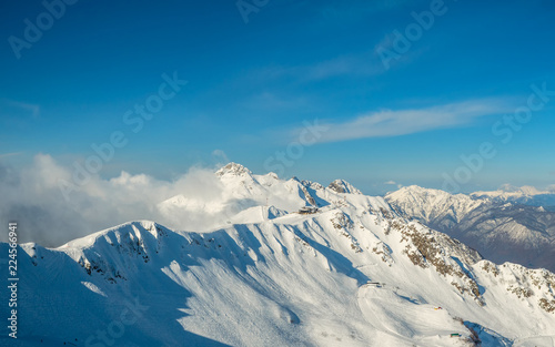 Beautiful snowy ridge of caucasus mountains under clear blue sky in Krasnaya Polyana, Sochi, Russia.