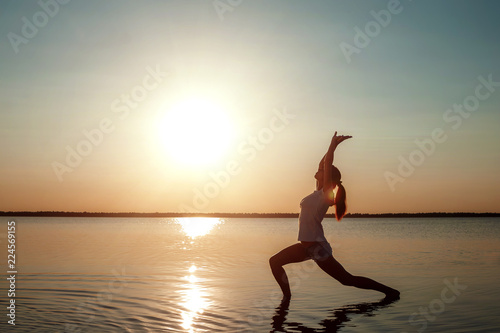 Young girl silhouette  yoga on nature  on a background of a lake and beautiful sunset. Fresh air  healthy way of life  pleasure  pacification.