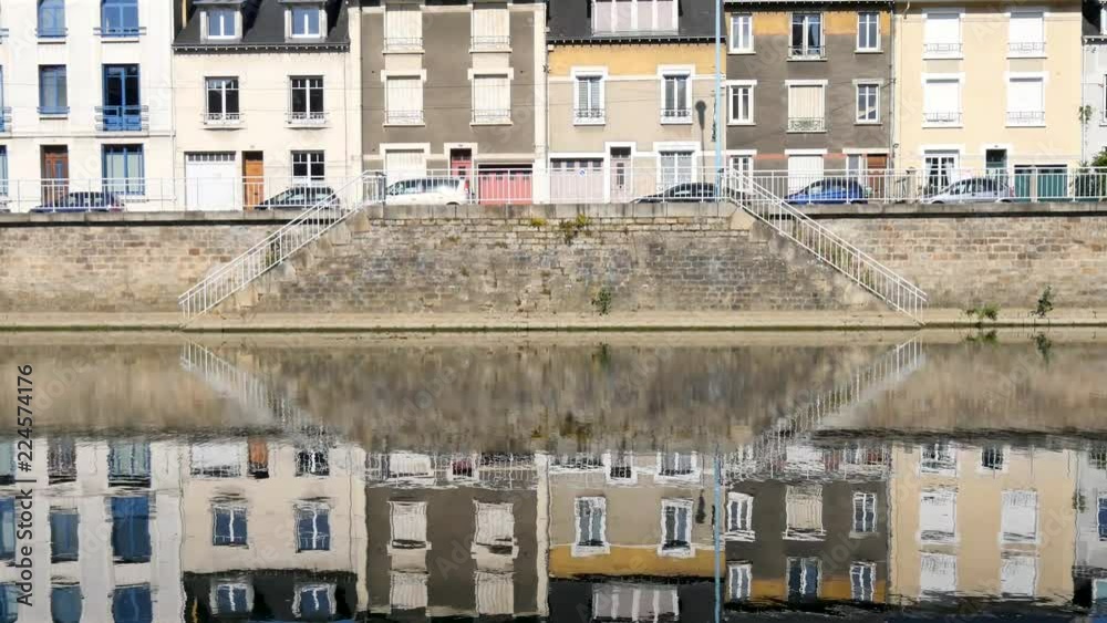 Buildings are reflected on the Sarthe River in the city of Le Mans in western France. Le Mans is an important city in the Pays de la Loire region. Filmed during the summer, sky with some clouds. Buildings are reflected on the Sarthe River in the city of Le Mans in western France. Le Mans is an important city in the Pays de la Loire region. Filmed during the summer, sky with some clouds.