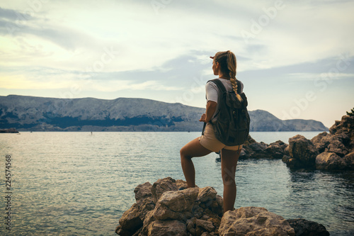 Traveller woman with backpack looking at sea bay