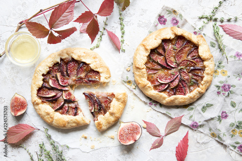 Crostata (pie) with cheese, figs, honey and thyme on grey background.