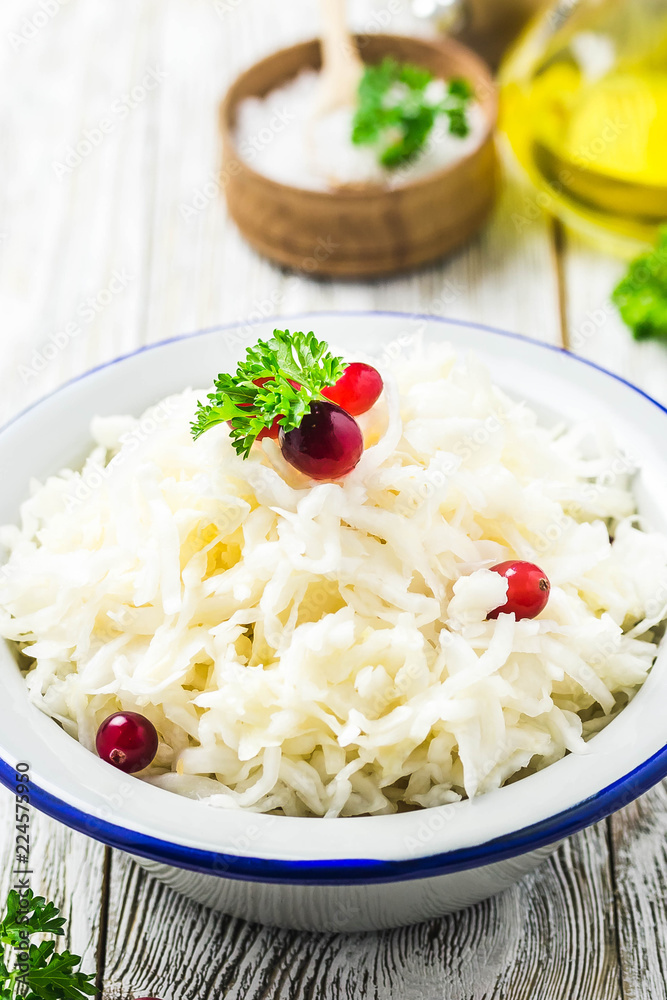Sauerkraut with parsley, cranberries in a bowl on wooden rustic background. Selective focus, space for text. Sauerkraut with parsley, cranberries in a bowl on wooden rustic background. Selective focus, space for text.