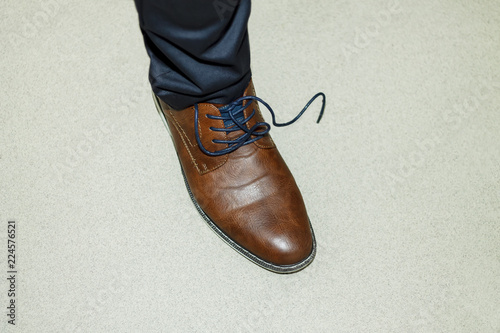 Male leg in a brown boot with the untied lace.