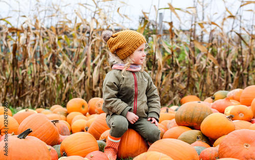 Little girl with pumpkin outdoor having fun in autumn park. photo