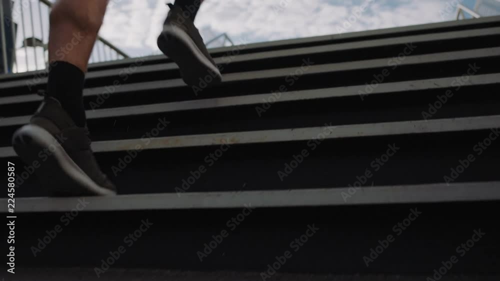 athlete man runner feet jogging up stairs training intense cardio workout exercise male athletic legs running on steps in urban city background close up