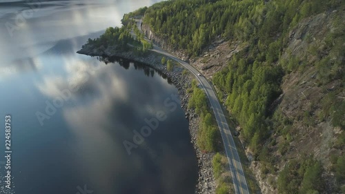 Flying Over Road with Car and Kroderen Lake Shore in Norway. Aerial Shot. Green Mountain with Trees. Drone is Flying Forward, Camera is Tilting Up photo