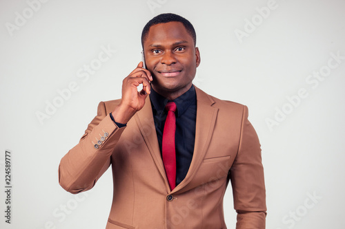 African Businessman Using Phone In Brown Suit, Black Shirt And Red Tie On  White Background In Studio Shot Stock Photo | Adobe Stock
