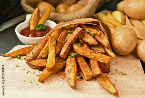 Homemade Crispy Seasoned French Fries..French fries  with spicy seasoning in brown paper bag on wooden broad.