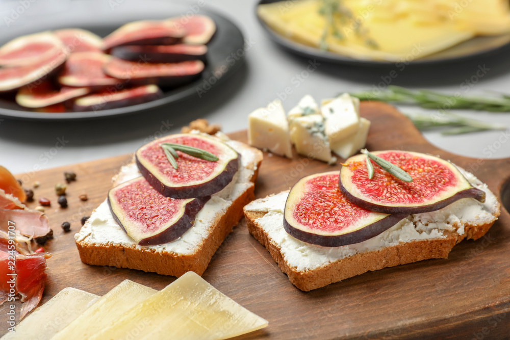 Sandwiches with ripe figs and cream cheese on wooden board