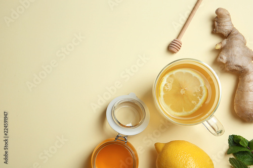 Flat lay composition with cup of lemon tea, ginger and honey on color background. Space for text