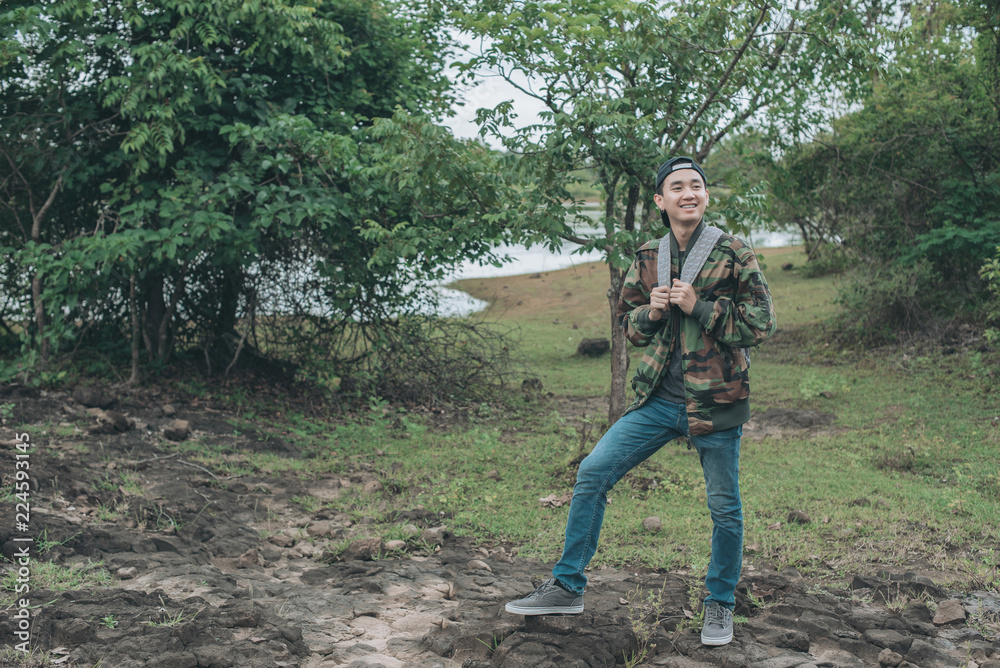 stylish hipster traveler walking in sunny forest in the mountains