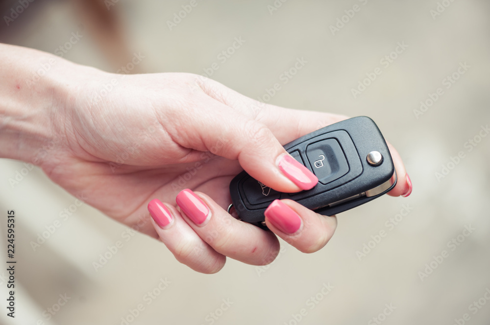 Fototapeta premium Key from the car in a female hand. Car seller. Opening and signaling