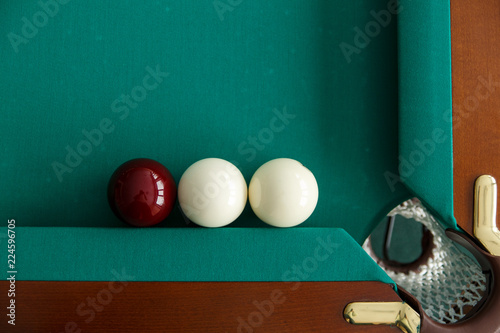 A pool table. Top view. The ball rolls into the pocket. Greencloth photo