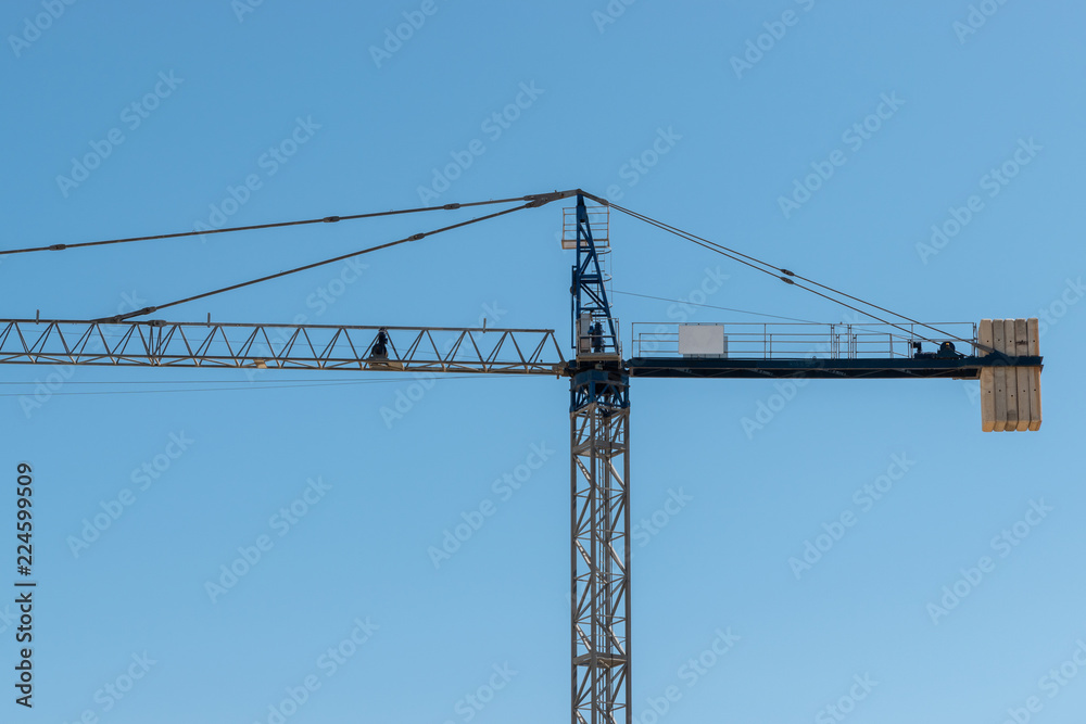 One Blue Construction site tower crane. with Bricks . Horizontal. Side view. Blue sky
