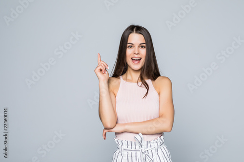 Portrait of excited young woman standing pointed with finger up isolated over gray background looking camera have an idea.