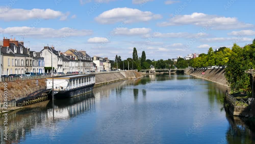 Buildings are reflected on the Sarthe River in the city of Le Mans in western France. Le Mans is an important city in the Pays de la Loire region. Filmed during the summer, sky with some clouds. Buildings are reflected on the Sarthe River in the city of Le Mans in western France. Le Mans is an important city in the Pays de la Loire region. Filmed during the summer, sky with some clouds.