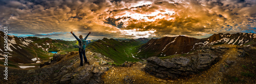 Young Woman Backpacker in Victory Pose with raised up arms on top of the Mountain Colorado USA Panoramic Shot