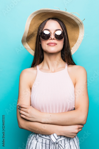 Close up portrait of happy young woman in beach hat and sunglasses isolated over blue background