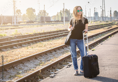 Woman with luggadge waiting on railway station for train on sunny day, going for travel or business meeting © STOATPHOTO