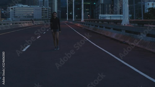 young woman runner athlete walking resting exhausted after running exercise workout in urban city at night