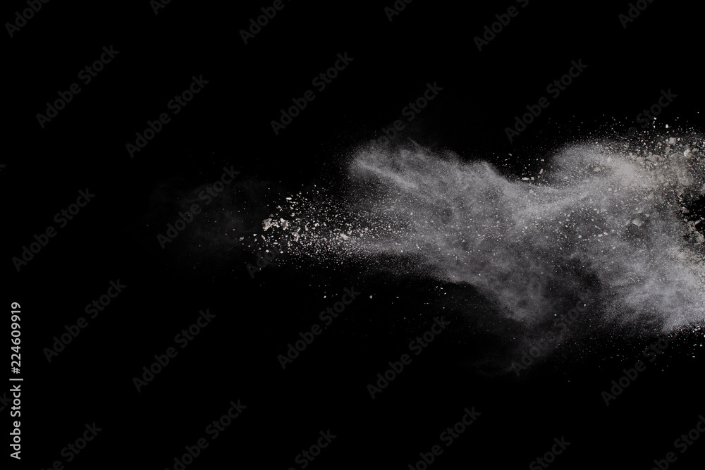 Freeze motion of white dust explosion on black background. Stopping the movement of white powder on dark background. Explosive powder white on black background.