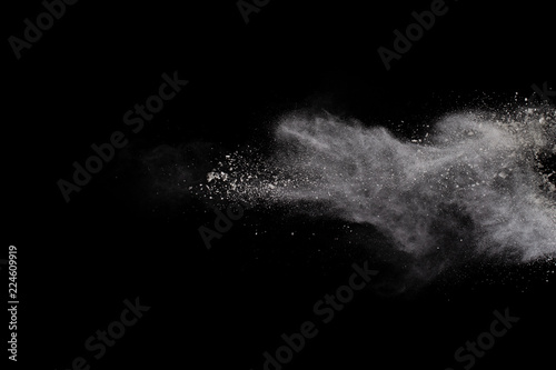Fototapeta Naklejka Na Ścianę i Meble -  Freeze motion of white dust explosion on black background. Stopping the movement of white powder on dark background. Explosive powder white on black background.
