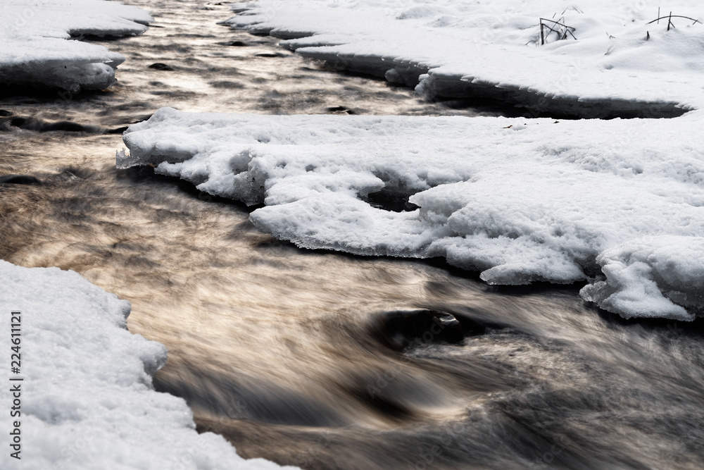 Wintery river view with reflection of colored atmospheric evening light, snow and ice on the shore, water movement in long exposure - Location: Germany, Saxony