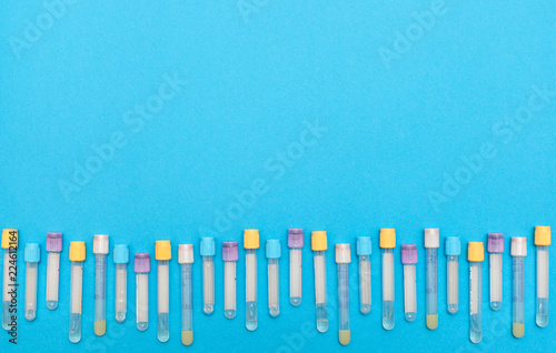 Flat lay  top view. Hematology blood analysis report with colorful sample collection tubes. Blood samples in a rack with space for text. Test tubes with blood in laboratory on blue background