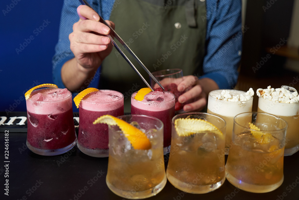 Professional Bartender is making fresh cocktail at bar counter, close-up Professional Bartender is making fresh cocktail at bar counter, close-up