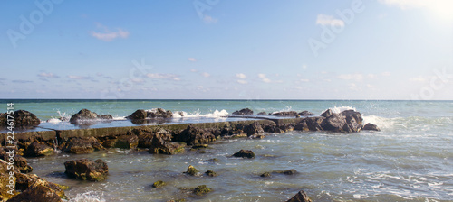 Sea pier with rocks under the sun