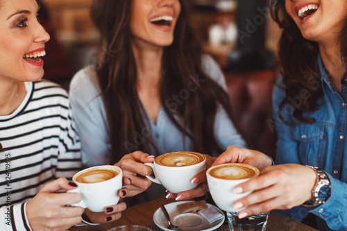 Fotografie, Obraz Three young women enjoy coffee at a coffee shop