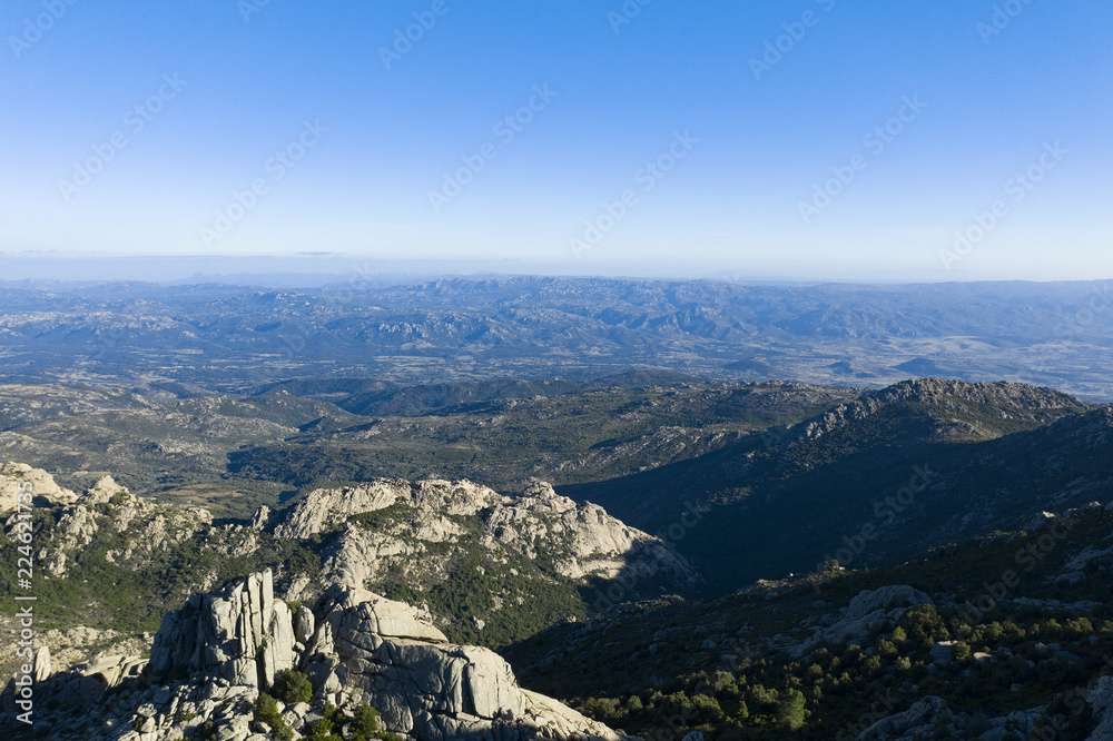 Aerial view of some spectacular mountains rich of green vegetation, pine trees and granite rocks. Sardinia, Italy.