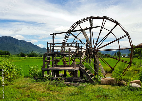 Large wooden turbine baler (water wheel) place on rice field and small canal at Thai-Dam Cultural Village in Chiang Khan, Loei Province, Thailand