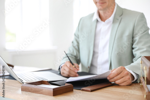 Male notary signing document at table in office, closeup