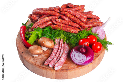 Hunting smoked sausages isolated on white background. Sausage with greens and vegetables on a wooden round board